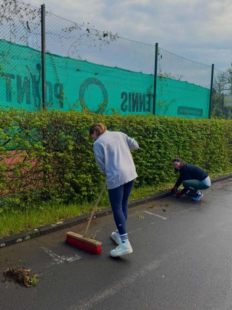 Vereinsmitglieder des TC31 reinigen die Wege und entfernen Unkraut am Rande des Tennisplatzes.